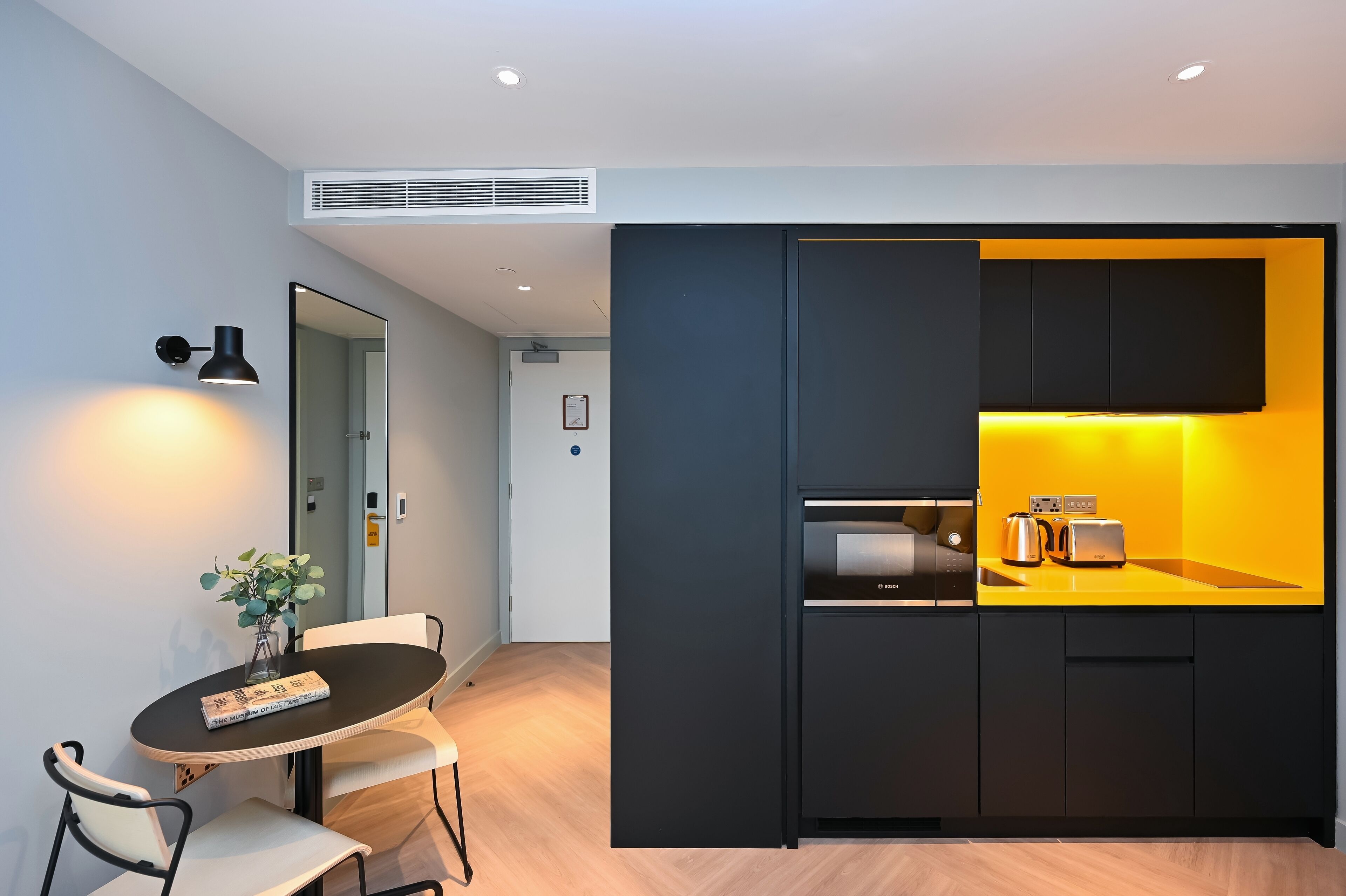A modern kitchen with a Bosch microwave, toaster, and kettle, and a dining area with a table and chairs.