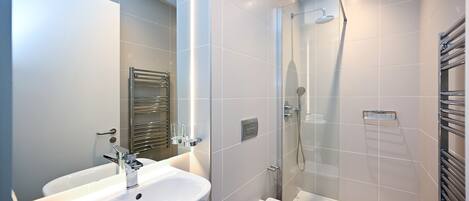 A modern bathroom with a white sink, toilet, and glass-enclosed shower.