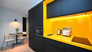 A modern kitchen with black cabinets, a yellow countertop, a built-in microwave, a toaster, and a sink.