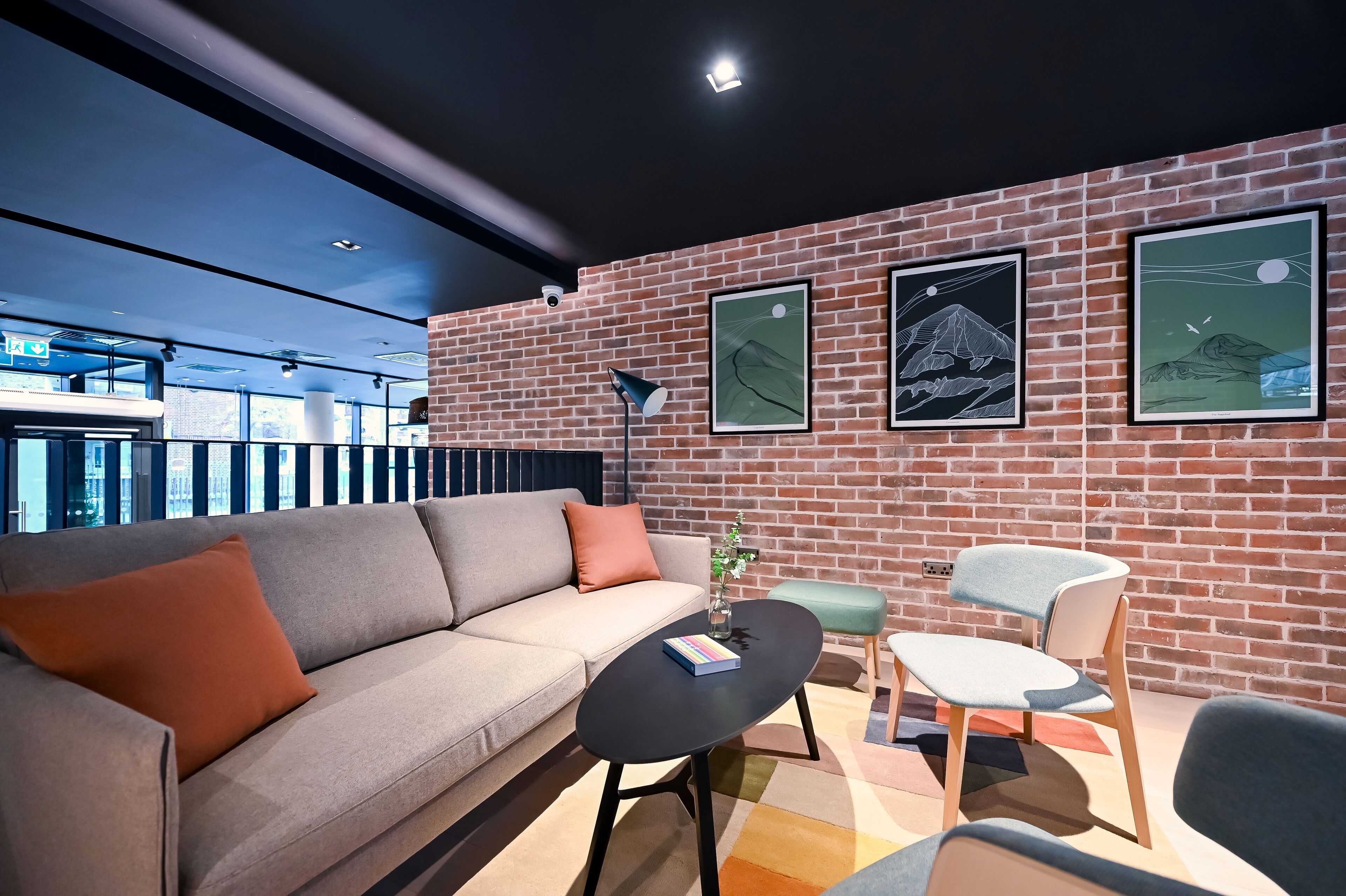 A modern lounge area with a brick wall, a sofa, a coffee table, and a chair.
