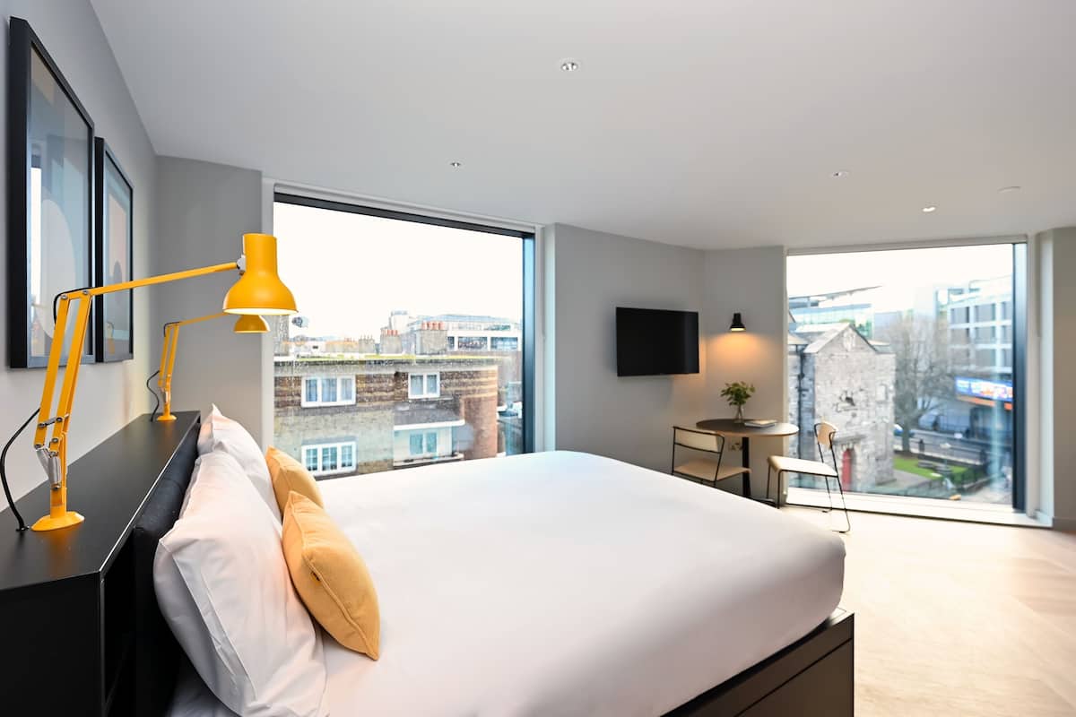 Ein modernes Hotelzimmer mit einem großen Bett, einem Schreibtisch, einem Sessel und einem Fernseher.