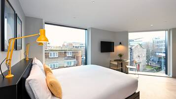 Una habitación de hotel moderna con una cama grande, un escritorio, una silla y un televisor.