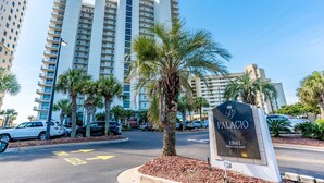 A hotel entrance with a sign reading "PALACIO 13661 PERDIDO KEY DRIVE" surrounded by palm trees and tall buildings. - Palacio 3/2 on 17th Floor with a Million Dollar View (Pensacola)