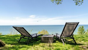 Twee ligstoelen gericht op een wateroppervlak, met een heldere lucht.