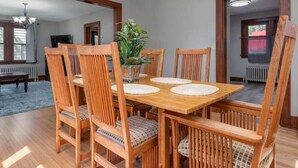 Comedor con mesa y sillas de madera, una araña y una planta en maceta.