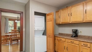 Una cocina con gabinetes de madera, una lavadora blanca y una cafetera.