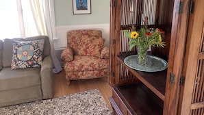 Un soggiorno con divano, poltrona e un mobile in legno con un vaso di fiori.