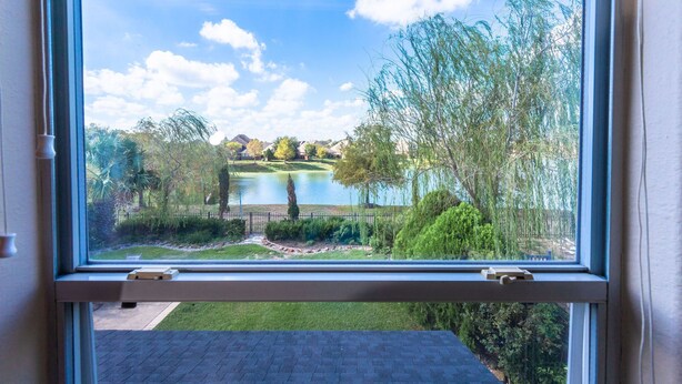 A window with a view of a lake, trees, and a grassy area. - WaterFront View 2 BDR 1.5 BA Home (Katy)