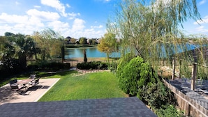 A patio with outdoor furniture, a grassy area, and a view of a lake with houses in the background. - WaterFront View 2 BDR 1.5 BA Home (Katy)