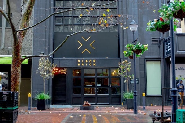 Un bâtiment avec une enseigne indiquant « BLACK BRICK » et une devanture de magasin ornée d’un néon avec l’inscription « The Experience Bar ».