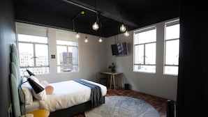Een moderne slaapkamer met een bed, een rond tapijt, een bureau en een televisie.