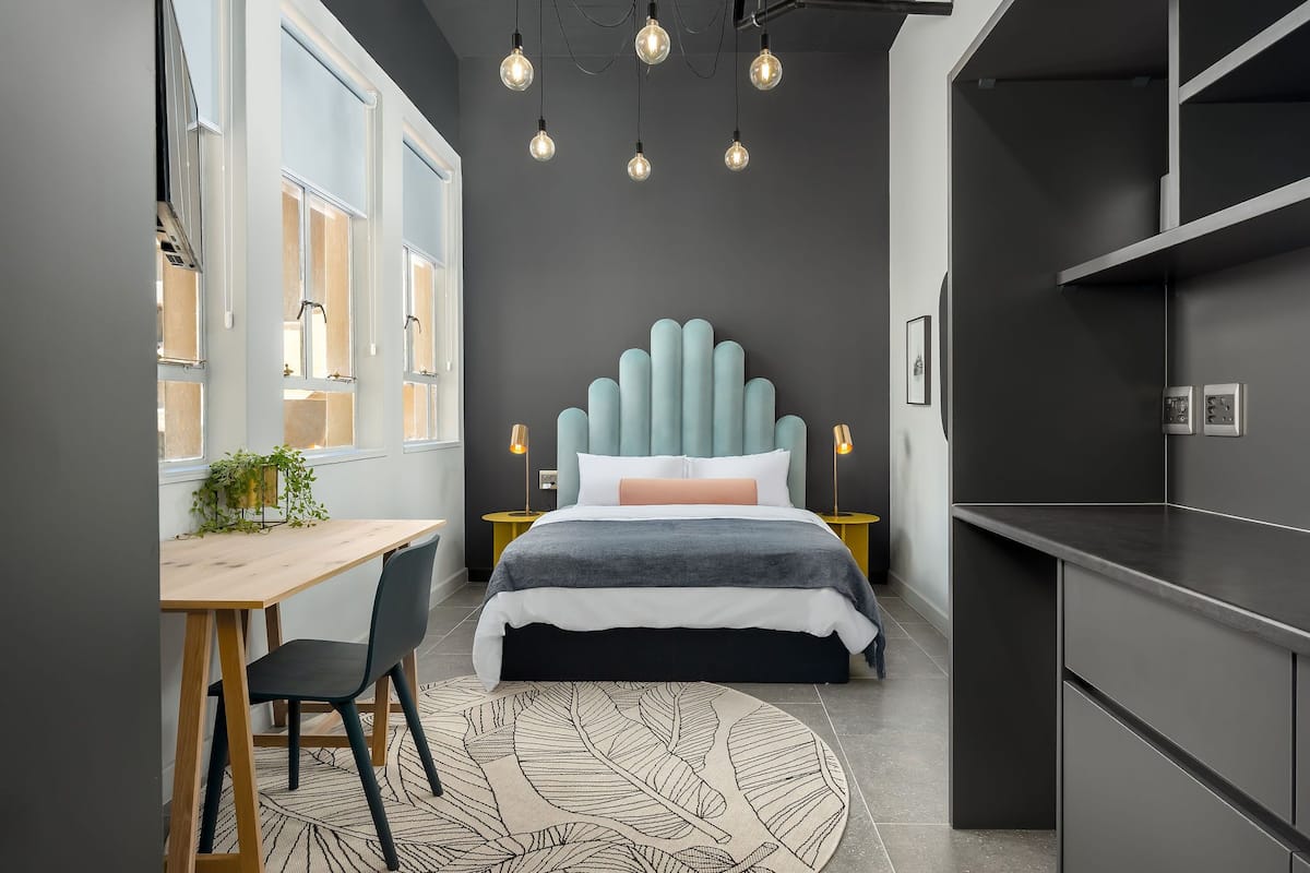 A modern bedroom with a bed, bedside tables, a desk, and a chair.