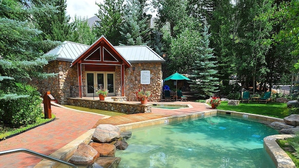 Ein Gebäude aus Stein mit einem Pool, umgeben von Bäumen und einer Terrassenanlage.