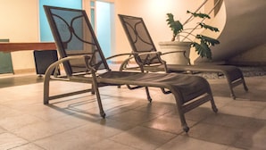 Una habitación con dos sillas de metal, una planta en maceta y una escalera.