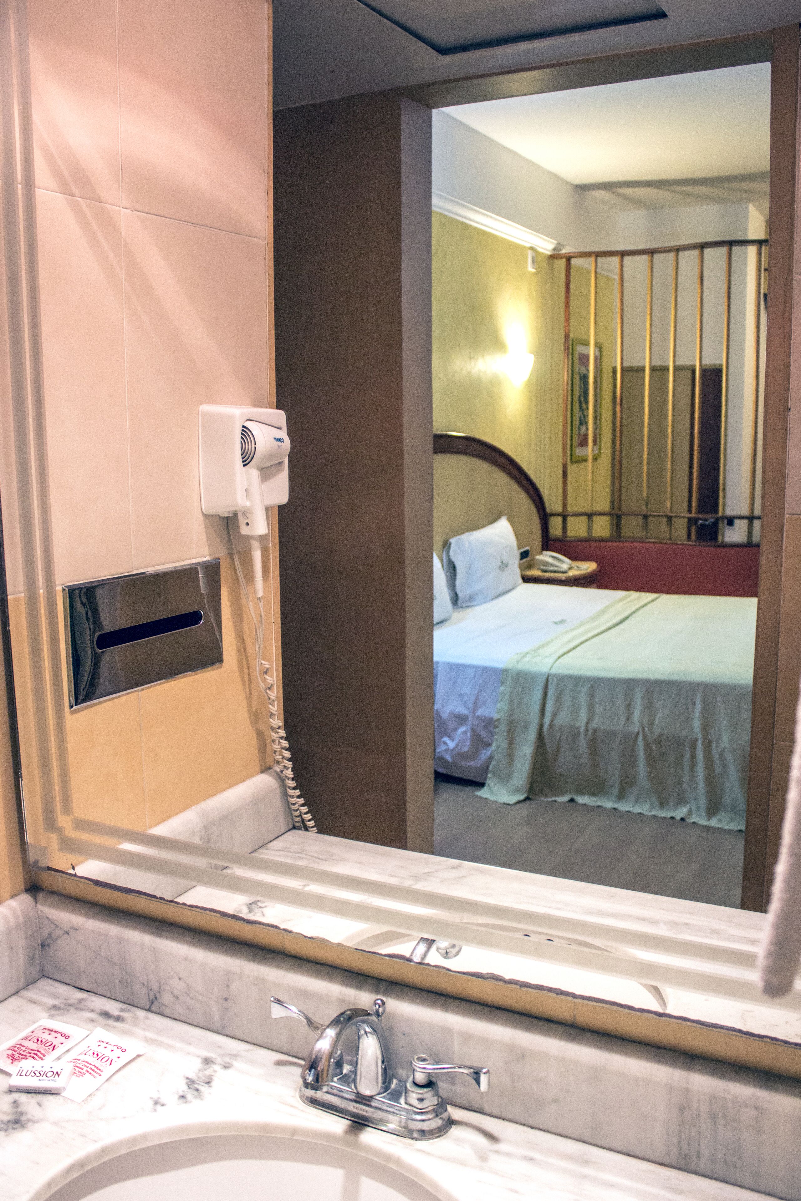 Un baño de hotel con un espejo grande, un secador de pelo y un lavamanos.