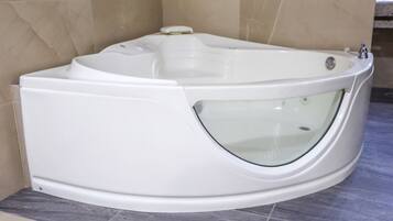 A modern bathtub with a glass-enclosed design, positioned in a bathroom with beige tiled walls and a marble floor.