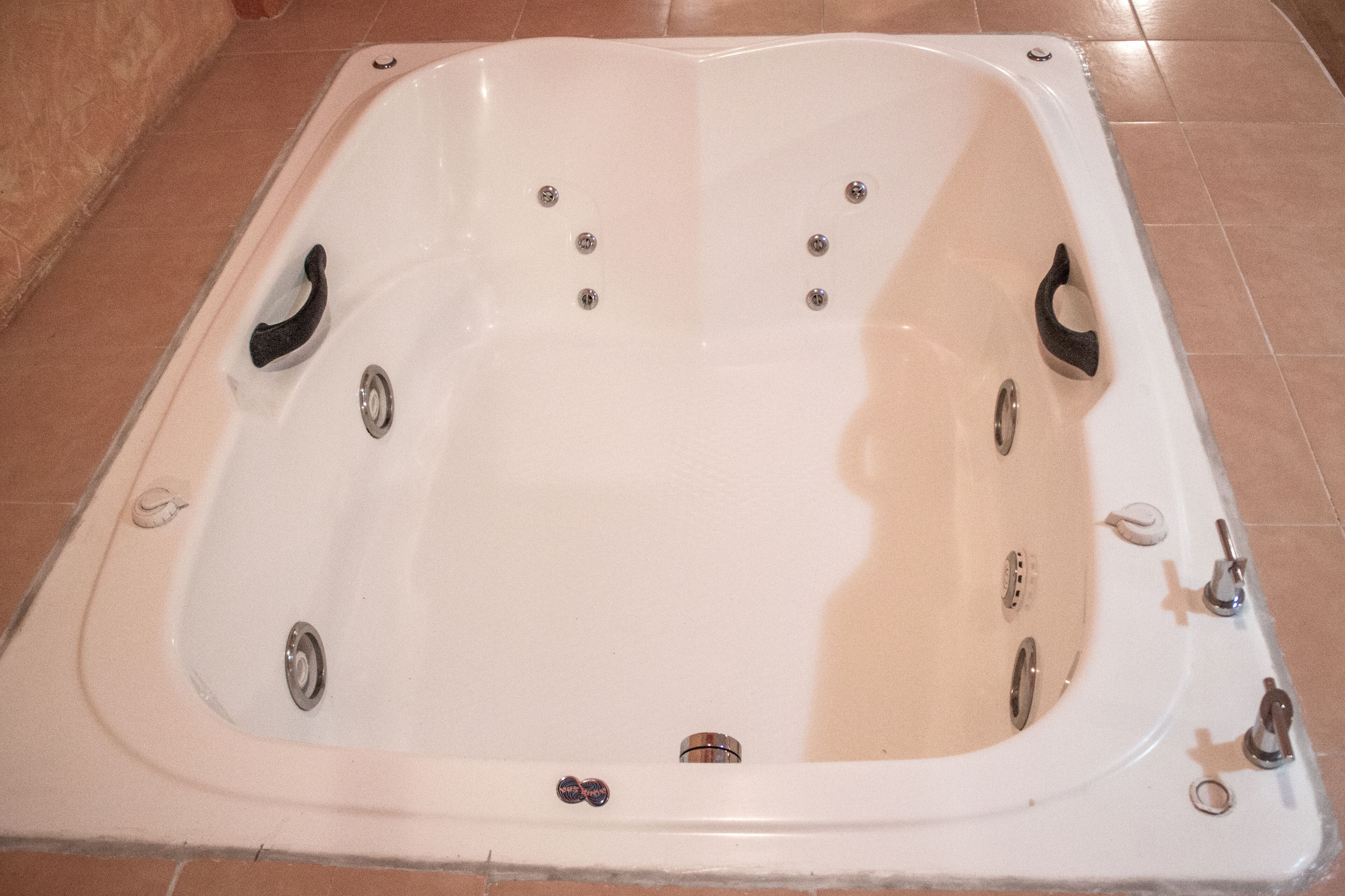 A white bathtub with multiple faucets and a drain.