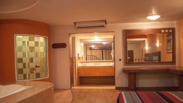 Un baño de hotel con un espejo grande, una bañera y un tocador con lavabo.
