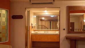 Un baño de hotel con bañera, lavamanos y espejo.