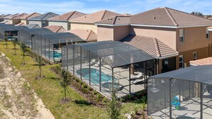 Un quartier résidentiel où les maisons se distinguent par leurs toits recouverts de tuiles rouges et où l’espace piscine est protégé par une structure de toit transparente.