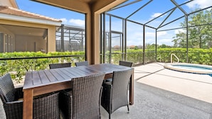Une terrasse extérieure avec une table en bois et des chaises en osier, une piscine et une vue sur le paysage environnant.