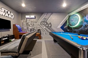 Habitación temática de Star Wars con mesa de billar, televisor y zona de estar.