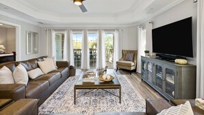 A spacious living room with a leather sofa, a coffee table, and a television on a cabinet.