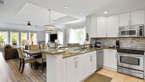 A spacious kitchen with white cabinets, stainless steel appliances, and a large island with a granite countertop.