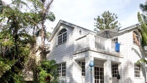 Une maison blanche à deux étages, avec une piscine en premier plan.
