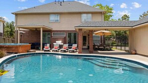 Una piscina con sillas de descanso y un jacuzzi en un patio trasero.