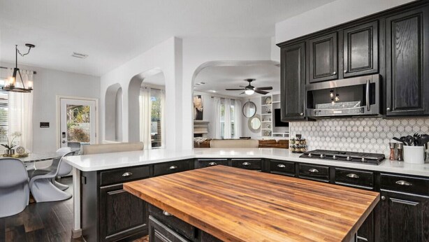 Una cocina moderna con armarios de madera oscura, una isla grande de madera y una encimera blanca.