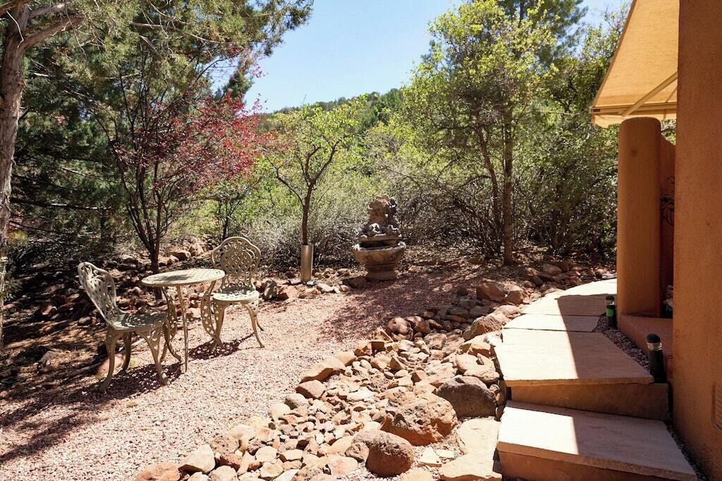 Une terrasse extérieure avec une table et des chaises, entourée de rochers et d’arbres.
