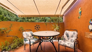 A patio with a round table and two chairs, surrounded by a low wall and plants. - RARE FIND! Star of Sedona Studio on Vortex land + Red Rock Views + Outdoor Room! (Sedona)