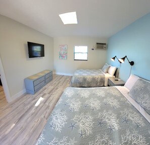 A bedroom with a bed, bedside table, TV, artwork, and a window. - Satellite Motel -  Shore to Please 109 (Treasure Island)