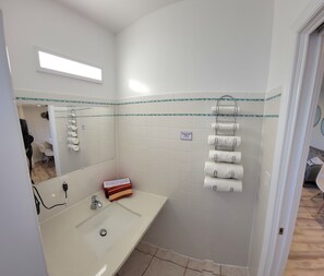 A bathroom with a white sink, a mirror, and a towel rack. - Satellite Motel -  Shore to Please 109 (Treasure Island)