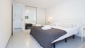 A modern hotel room with a large bed, a bedside table, a mirror, and a door leading to a bathroom.