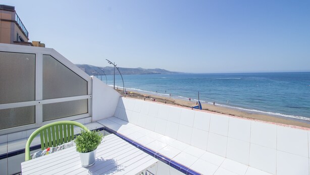 A balcony with a view of the beach and ocean.
