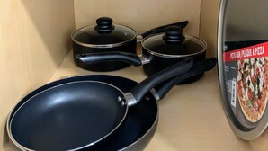 Une étagère de cuisine contenant des ustensiles de cuisine, notamment une poêle, une casserole et une marmite.