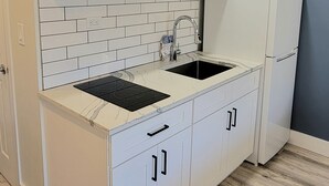 Une cuisine moderne avec des meubles blancs, un plan de travail noir et un pare-feu en carreaux.