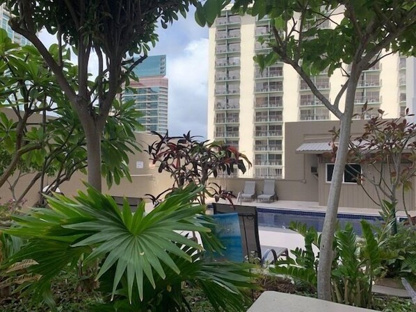 Edificio residencial con balcones, rodeado de exuberante vegetación y una piscina.