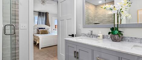 Une salle de bain moderne avec un grand miroir, un comptoir en marbre et une orchidée en pot.