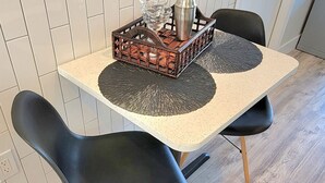 A kitchen with a white tiled backsplash, a wooden floor, and two black chairs with wooden legs. - Satellite Motel - Shore Thing 111 (Treasure Island)