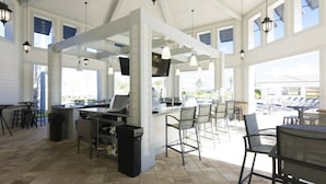 A spacious outdoor dining area with a bar, multiple seating arrangements, and large windows providing natural light. - Luxurious Apartment 2BR/2BA • Near Disney • Storey Lake Resort [SL47315] (Kissimmee)