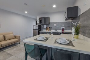 Een moderne keuken met een centraal eiland, eettafelsstoelen, een bank en een potplant.