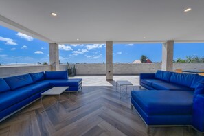 Una terraza en la azotea con sofás azules, una pequeña mesa y vistas al horizonte de la ciudad.