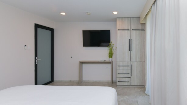 A bedroom with a bed, a desk, a television, and a wardrobe.