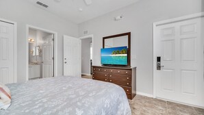 A bedroom with a bed, dresser, TV, and white doors. - Cozy, Resort Home Close To Disney (Davenport)
