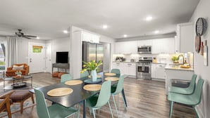 Una cocina moderna con armarios blancos, un refrigerador de acero inoxidable y un microondas.