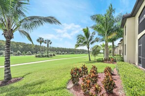 A well-maintained lawn, palm trees, and a building with a large garage door.