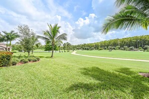 A well-maintained golf course with a clear path, palm trees, and a residential area in the background.